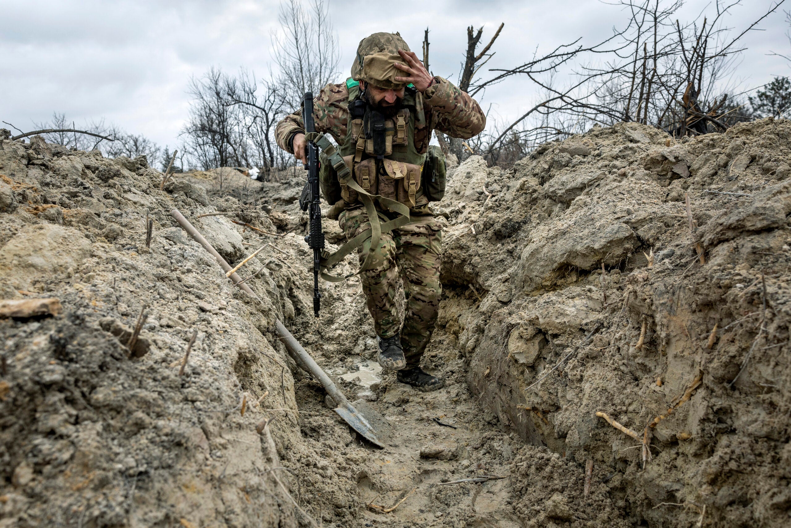 BAKHMUT, UKRAINE - MARCH 05:  Ukrainian medic "Doc" with the 28th Brigade runs through a partially dug trench along the frontline on March 05, 2023 outside of Bakhmut, Ukraine. The Ukrainian Army medic, an Odessa dentist in civilian life, said was a guitarist in band Uragan Metal for 13 years before he joined the Army following the Russian invasion. Russian forces have been attacking Ukrainian troops as part of an offensive to encircle Bakhmut in Ukraine's eastern Donbas region. (Photo by John Moore/Getty Images)