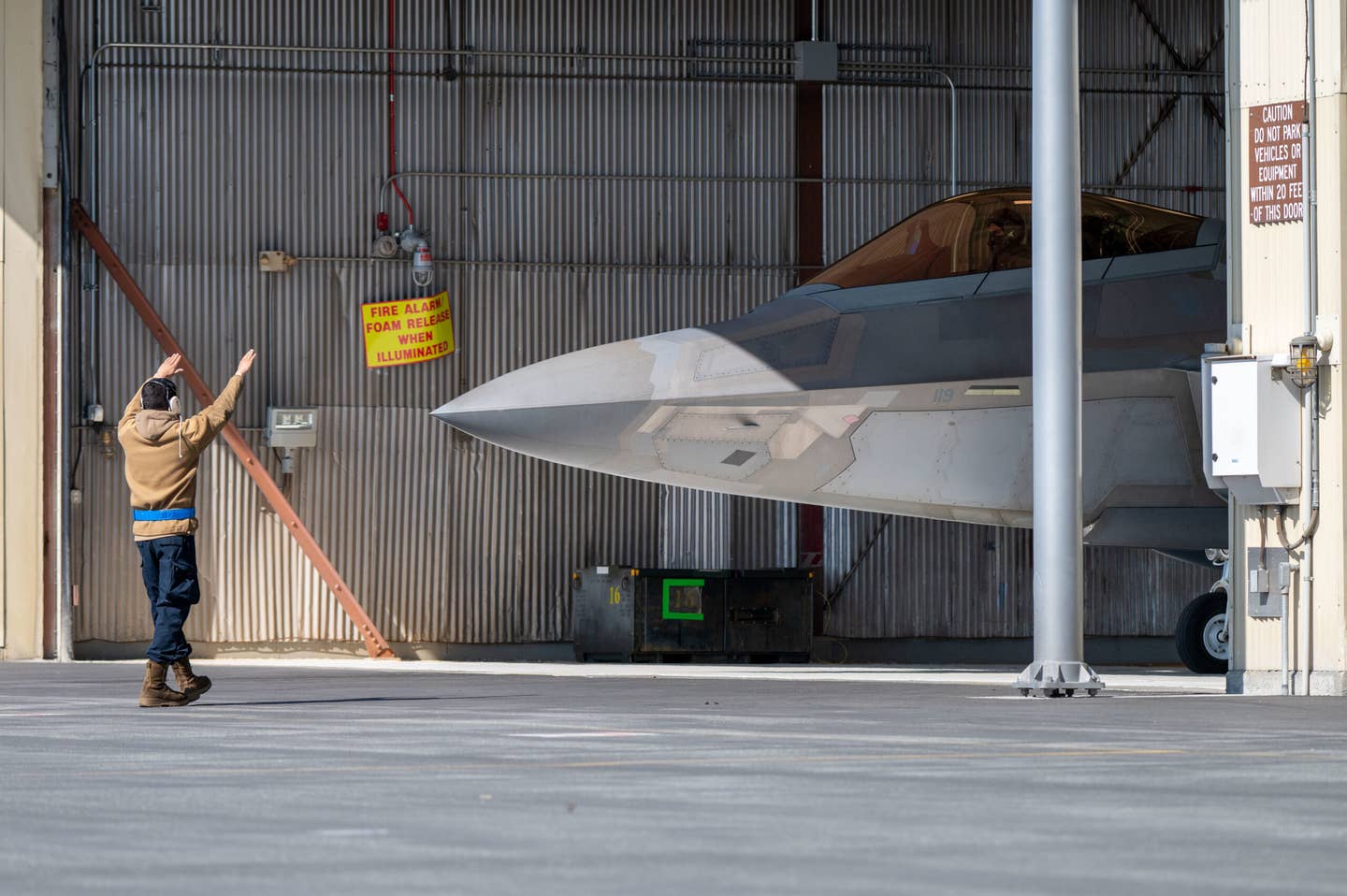 A U.S. Air Force Airman assigned to the 3rd Wing marshals an F-22 Raptor out of its hangar before a sortie with U.S. Air Force F-15 Eagles assigned to the California Air National Guard’s 144th Fighter Wing at Joint Base Elmendorf-Richardson, Alaska, April 18, 2022. The Eagles deployed to Alaska to improve interoperability with JBER Raptor’s real-world alert mission. (U.S. Air Force photo by Airman 1st Class Andrew Britten)