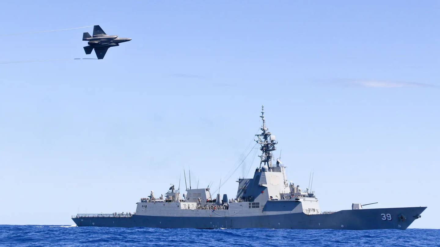 A Royal Australian Air Force F-35A Lightning conducts a flypast over HMAS <em>Hobart</em> during Exercise TASMAN SHIELD 21, off the east coast of Australia. Both these platforms are now set to receive new long-range strike missiles. <em>Australian Department of Defense</em>