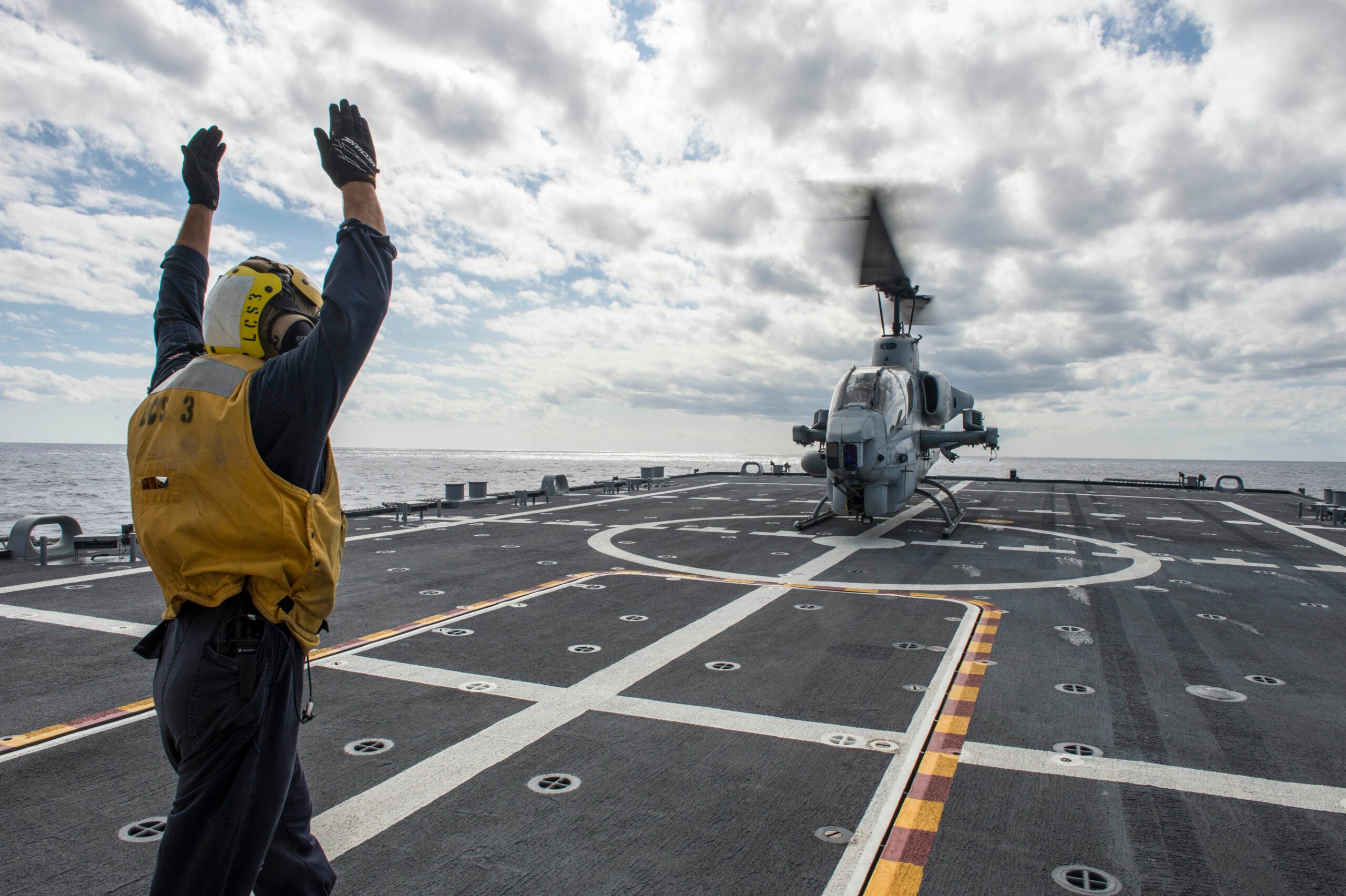 Boatswain's Mate 2nd Class Adam Garnett from Anchorage, Alaska, signals an AH-1 Cobra helicopter from Marine Air Group (MAG) 24 during deck landing qualification training aboard the littoral combat ship USS Fort Worth (LCS 3). Fort Worth departed its home port of San Diego Nov. 17 for a 16-month rotational deployment to Southeast Asia in support of the Navy’s strategic rebalance to the Pacific. (U.S. Navy photo by Mass Communication Specialist 2nd Class Antonio P. Turretto Ramos)