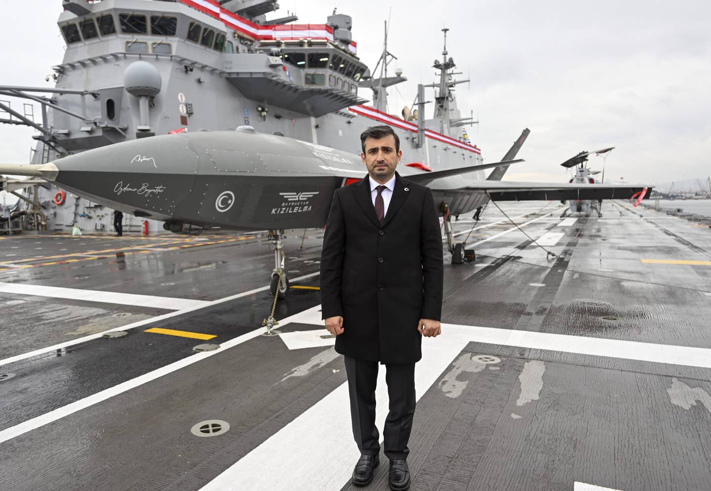 Chairman of the board and the chief technology officer of Baykar, Selcuk Bayraktar, poses for a photo in front of the Kizilelma on the deck of TCG <em>Anadolu</em>. <em>Credit: Photo by Serhat Cagdas/Anadolu Agency via Getty Images</em>