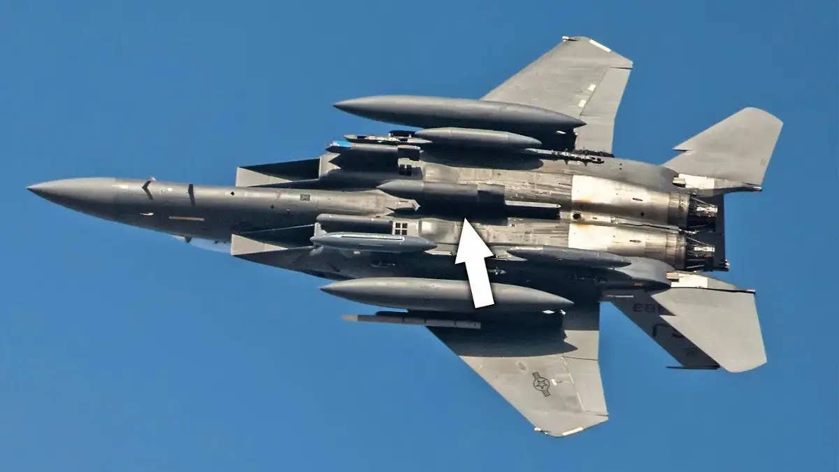 A picture of an F-15E Strike Eagle with an arrow pointing to the Dragon's Eye radar pod on its centerline pylon. <em>USAF</em>