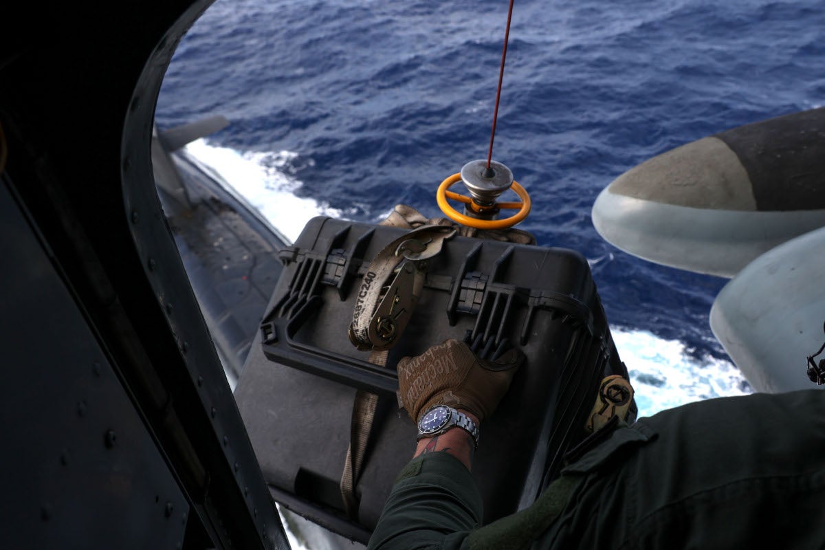 U.S. Marine Corps Staff Sgt. Joseph McDonnell, a crew chief with Marine Heavy Helicopter Squadron (HMH) 462, 1st Marine Aircraft Wing, III Marine Expeditionary Force, lowers a package to the Ohio-class ballistic missile submarine USS Maine (SSBN 741) during a vertical replenishment (VERTREP) in the Philippine Sea, May 9, 2023. Vertical Replenishments enable naval vessels to quickly receive critical resources without disrupting maritime security operations while underway. III MEF is postured to enable naval expeditionary operations within the first island chain as part of a Stand-in-Force. (U.S. Marine Corps photo by Lance Cpl. Emily Weiss)