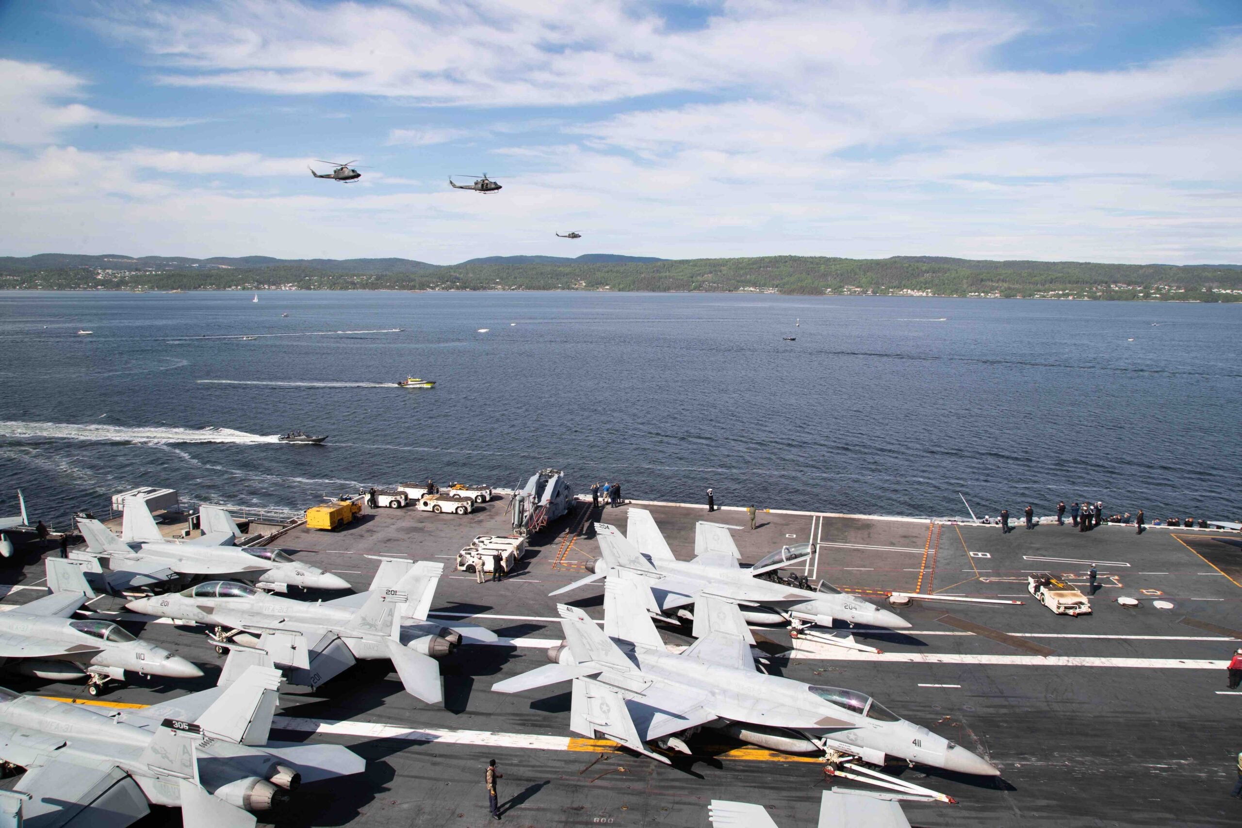 Three Norwegian military helicopters perform a fly-by of the flagship USS Gerald R. Ford (CVN 78) as the ship transits the Oslo fjord for its first port call in Oslo, Norway, May 24, 2023. Gerald R. Ford is the first U.S. aircraft carrier to pull into Norway in more than 65 years. Gerald R. Ford is the U.S. Navy’s newest and most advanced aircraft carrier, representing a generational leap in the in the U.S. Navy’s capacity to project power on a global scale. The Gerald R. Ford Strike Group is on a scheduled deployment in the U.S. Naval Forces Europe area of operations, employed by U.S. Sixth Fleet to defend U.S., allied, and partner interest. (US Navy Photo by Mass Communication Specialist 2nd Class Brian Glunt) Released