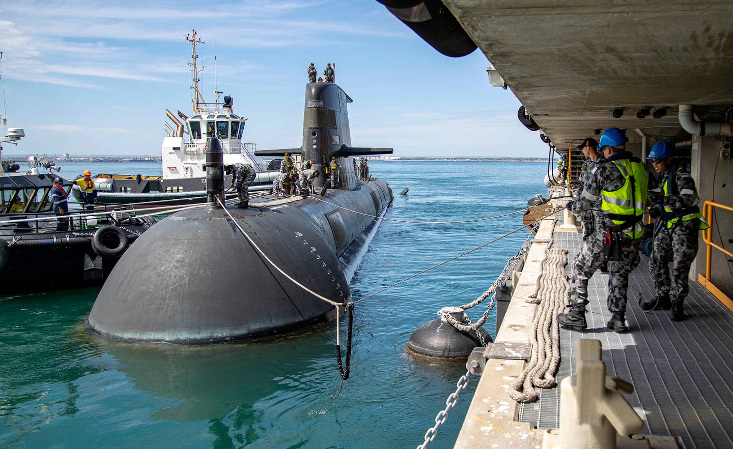 Sailors heave in on berthing lines as the <em>Collins</em> class submarine HMAS <em>Farncomb</em> comes alongside Diamantina Pier upon its return to Fleet Base West in Western Australia in March 2020. <em>Australian Department of Defense</em>