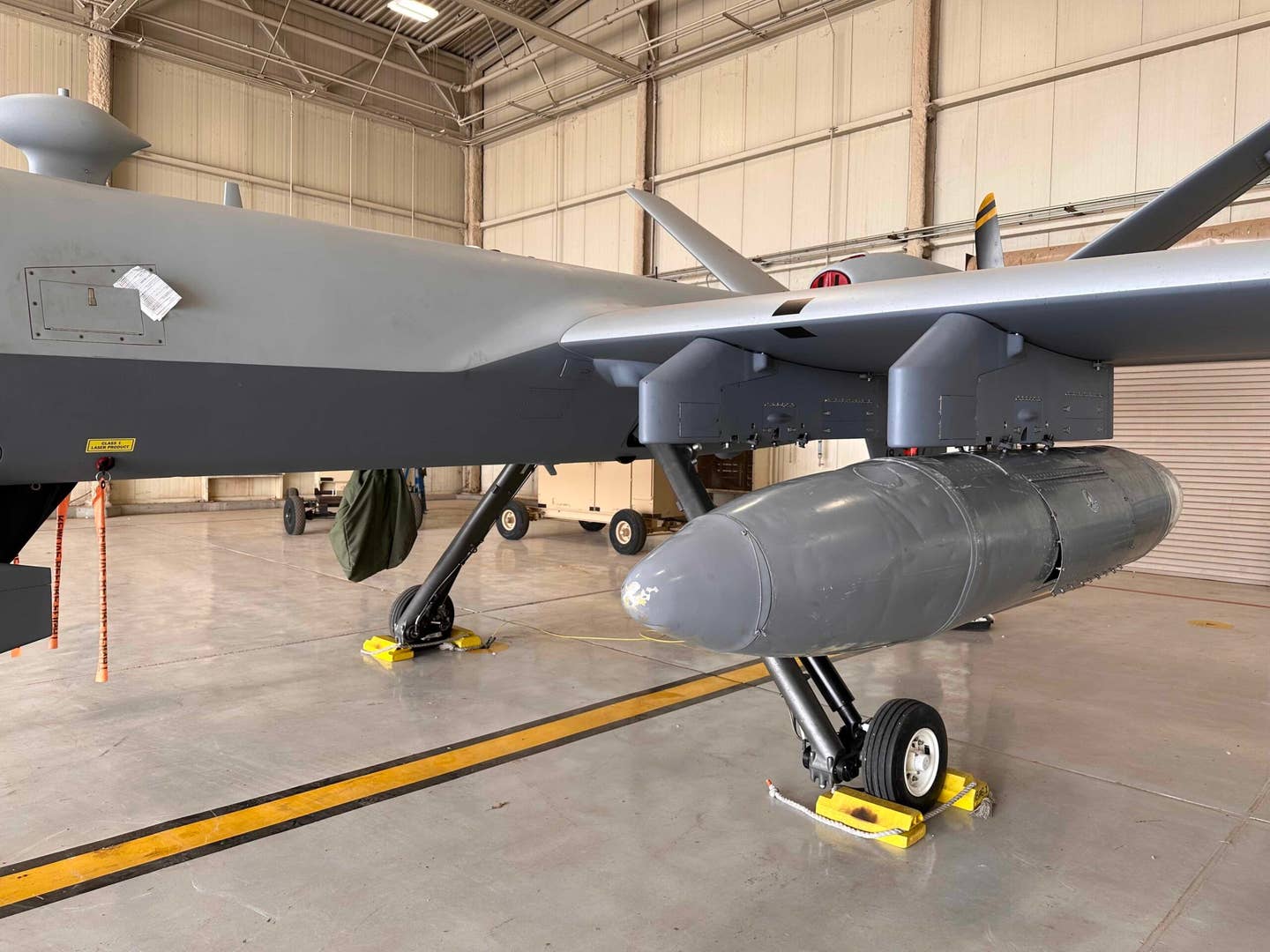 A MQ-9 Reaper rests inside a hangar at Cannon Air Force Base, New Mexico, June 7, 2023. The attached travel pod allows combatant commanders to use the MQ-9 Reaper to deliver vital supplies in a confined area instead of relying on a cargo aircraft. <em>U.S. Air Force photo by Maj. Doniell Mojazza</em>