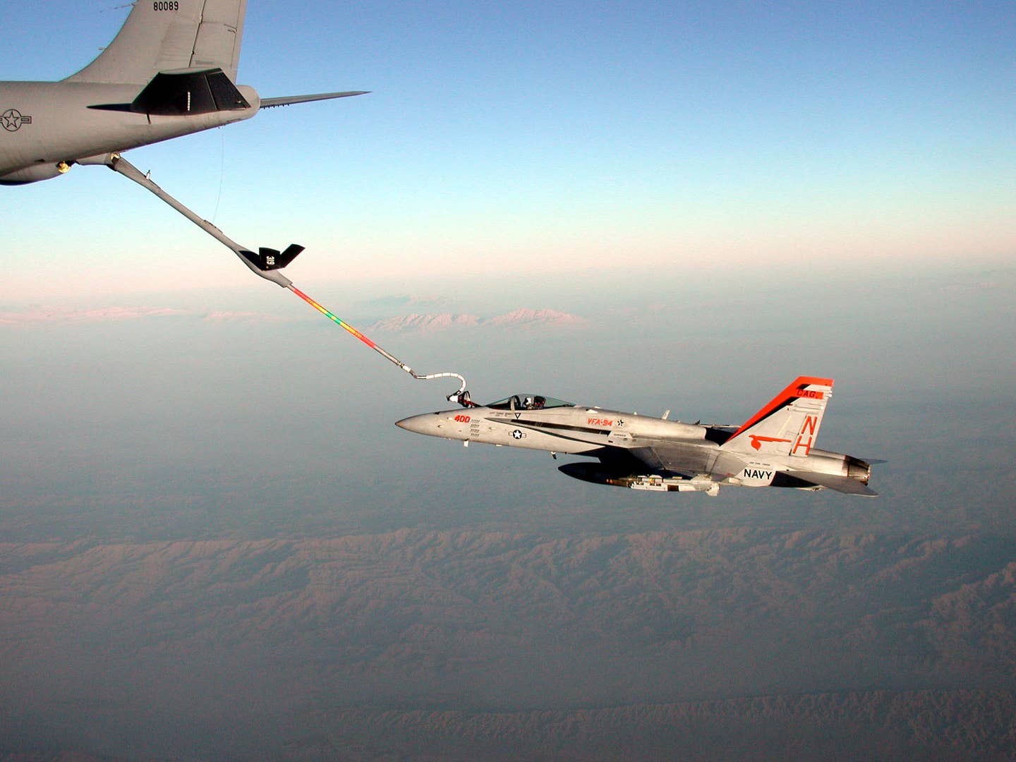 A U.S. Navy F/A-18C Hornet fighter uses a boom-drogue adapter kit to receive fuel from a U.S. Air Force KC-135 tanker. <em>Photo by Mai/Getty Images</em>