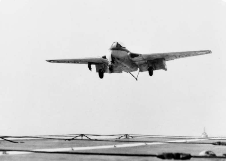 A Royal Navy Sea Vampire comes in to land on the deck of the aircraft carrier HMS <em>Vengeance</em>, in 1951. This is a conventional recovery on a standard carrier deck, using an arresting wire and trailing hook. <em>Royal Navy</em>