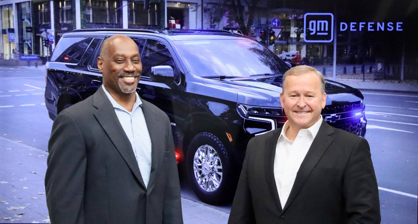 Assistant Secretary Smith and GM Defense President Stephen duMont stand in front of an image of the new first-of-its-kind, purpose-built heavy-duty SUV, June 29, 2023. <em>Department of State</em>