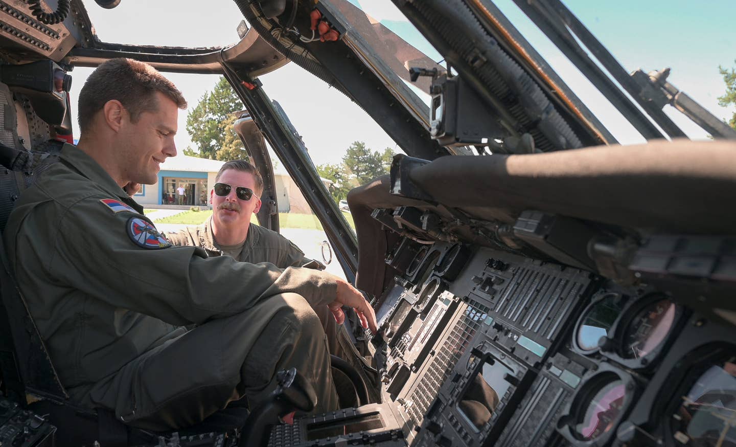 U.S. Air Force Capt. Samuel Unke, 56th Rescue Squadron pilot, demonstrates the capabilities of a U.S. Air Force HH-60G Pave Hawk helicopter to a Serbian Air Force pilot assigned to the 890th Mixed Helicopter Squadron, at Sgt./Pilot Mihajlo Petrovic Air Base, Serbia, Aug. 9, 2023. <em>U.S. Air Force photo by Airman 1st Class Edgar Grimaldo</em>