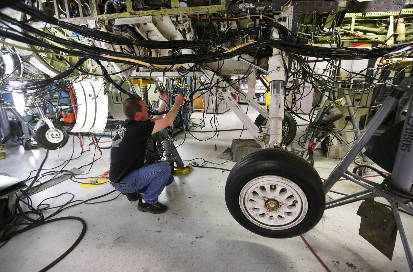 An aircraft mechanic works on then underside of an F-16 Falcon at Hill Air Force base in Ogden, Utah.  (Photo by George Frey/Getty Images)