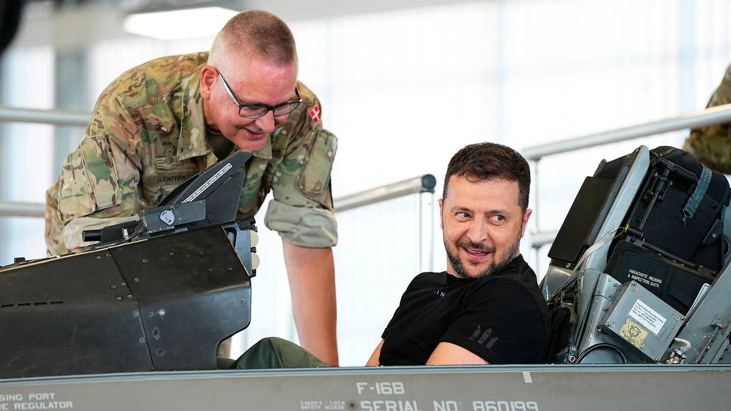 Ukrainian President Volodymyr Zelensky (R) reacts as he sits in a F-16 fighter jet in the hangar of the Skrydstrup Airbase in Vojens, northern Denmark, on August 20, 2023. (Photo by MADS CLAUS RASMUSSEN/Ritzau Scanpix/AFP via Getty Images)