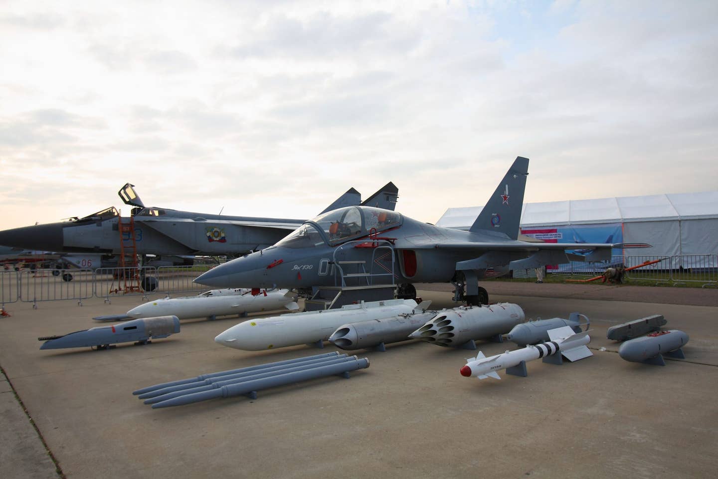 A Russian Yak-130 on display at the 2013 MAKS airshow alongside its potential armaments and a MiG-31 Foxhound. <em>Wikimedia Commons</em>.