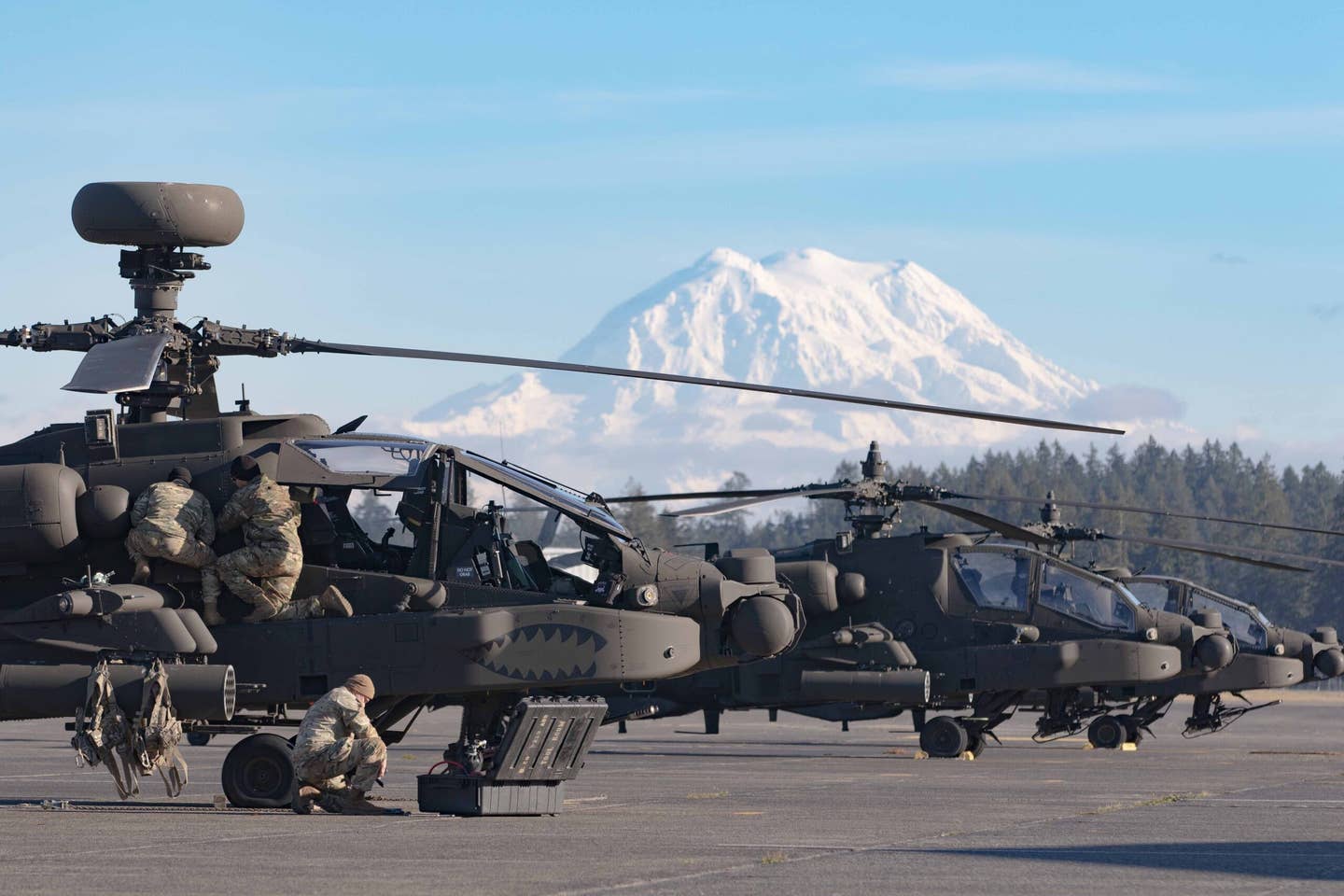 An AH-64 with its mast-mounted radar and two other AH-64s with earlier, less capable MUMT installations on their rotor hubs that predated MUMT-X seen at Fort Lewis. (U.S. Army photo by Capt. Kyle Abraham, 16th Combat Aviation Brigade)