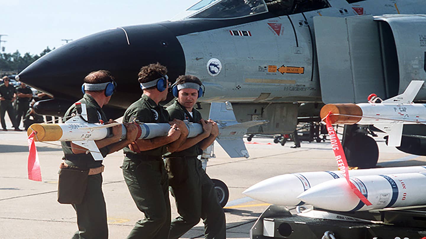 USAF weapons loaders carry an AIM-9 Sidewinder to an F-4 Phantom II during William Tell 1986. <em>USAF</em>