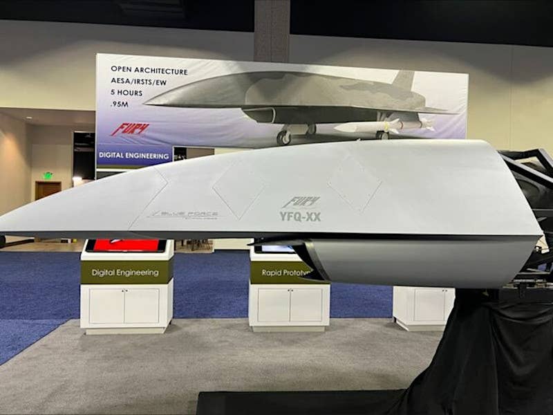 A view of Blue Force Technologies' booth at a past iteration of the Air &amp; Space Forces Association's main annual conference in Washington, D.C., with concept art showing an AIM-120 missile-armed Fury and a nose section with the notional YFQ-XX nomenclature written on the side. <em>Andrew Van Timmeren/LinkedIn</em>