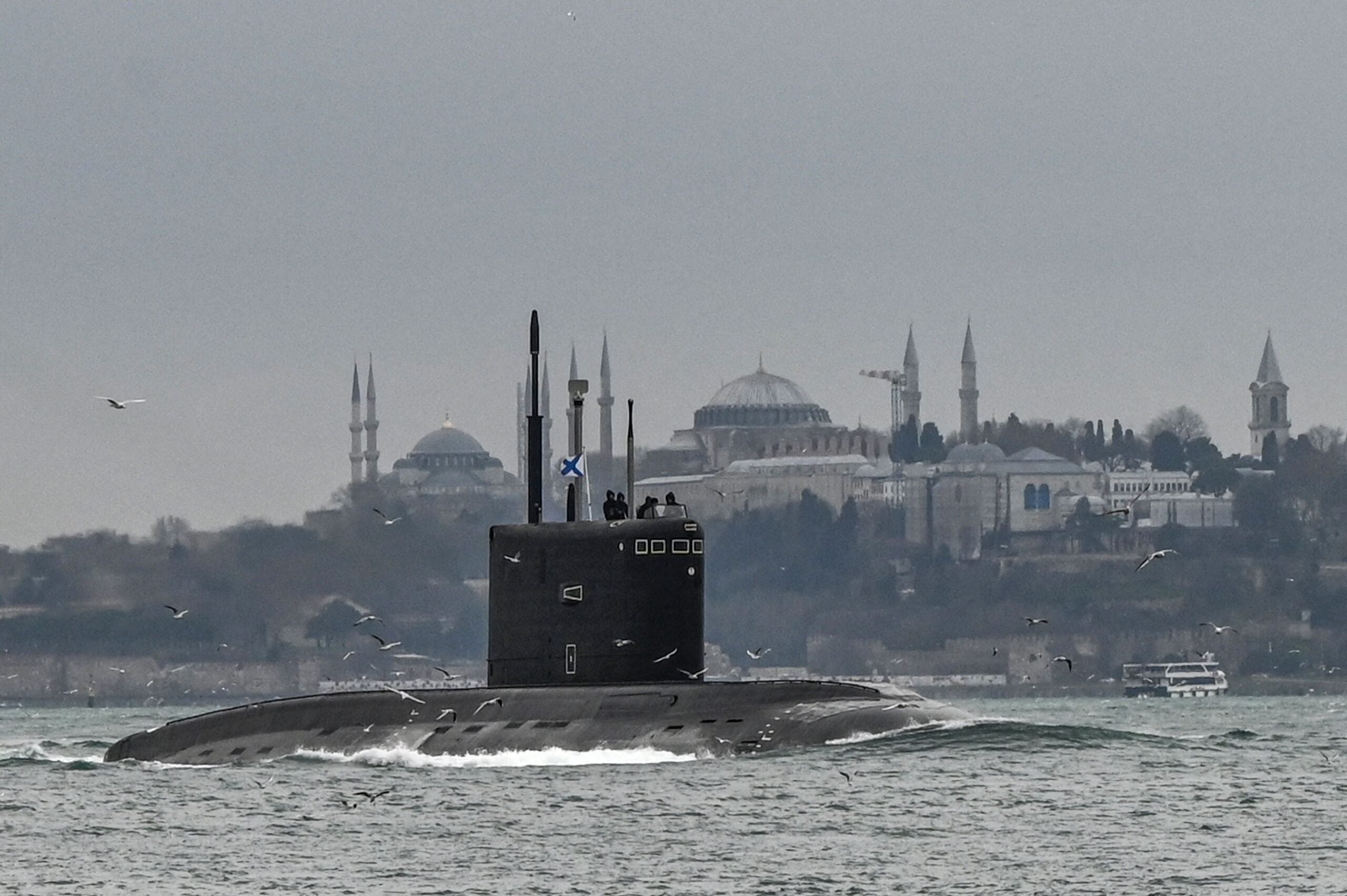 TOPSHOT - Russian Navy's diesel-electric Kilo class submarine Rostov-on-Don sails with an naval ensign of the Russian Federation, also known in Russian as The Andreyevsky Flag on it through the Bosphorus Strait on the way to the Black Sea past the city Istanbul as Sultanahmet mosque (L) and Hagia Sophia mosque (R) are seen in the backround on February 13, 2022. (Photo by Ozan KOSE / AFP) (Photo by OZAN KOSE/AFP via Getty Images)
