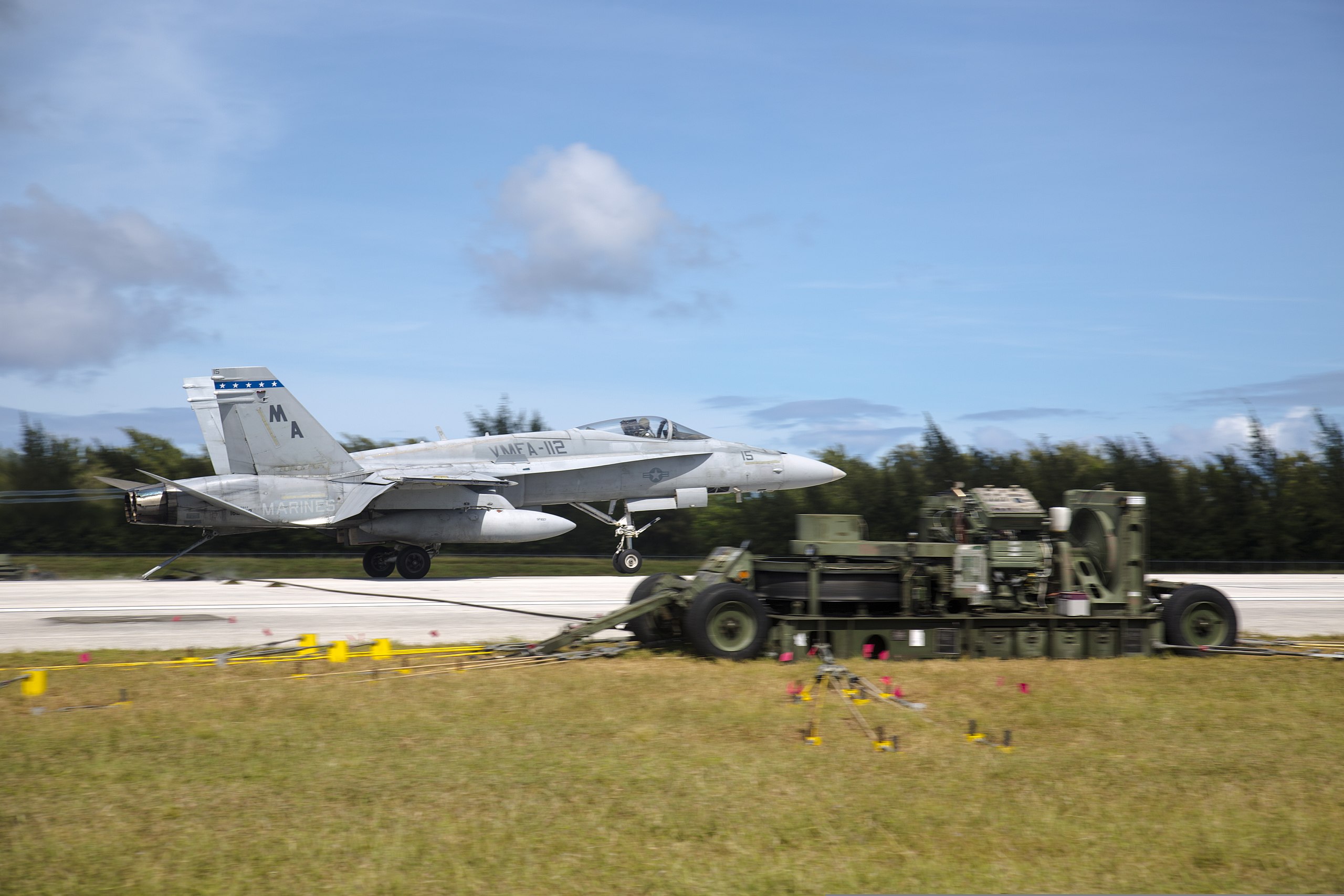 An F/A-18D Hornet lands on the runway to be stopped by M-31 Marine Corps expeditionary arresting gear systems Dec. 5 at Tinian's West Field during exercise Forager Fury II. The training consisted of rapid ground refueling and arrested landing operations, extending aviation training throughout the Mariana Island Range Complex. During this training, Marine aviation units are able to practice, train for, and execute the six functions of Marine aviation: assault support, anti-aircraft warfare, offensive air support, electronic warfare, control of aircraft and missiles, and aerial reconnaissance. The squadrons that participated in the training were Marine Fighter Attack Squadron 112, "The Cowboys," from Fort Worth, Texas, and VMFA 232, "The Red Devils," from Marine Corps Air Station Miramar, Calif., who are currently deployed to MCAS Iwakuni, Japan, under the unit deployment program with MAG-12. (U.S. Marine Photo by Lance Cpl. Antonio Rubio/Released)