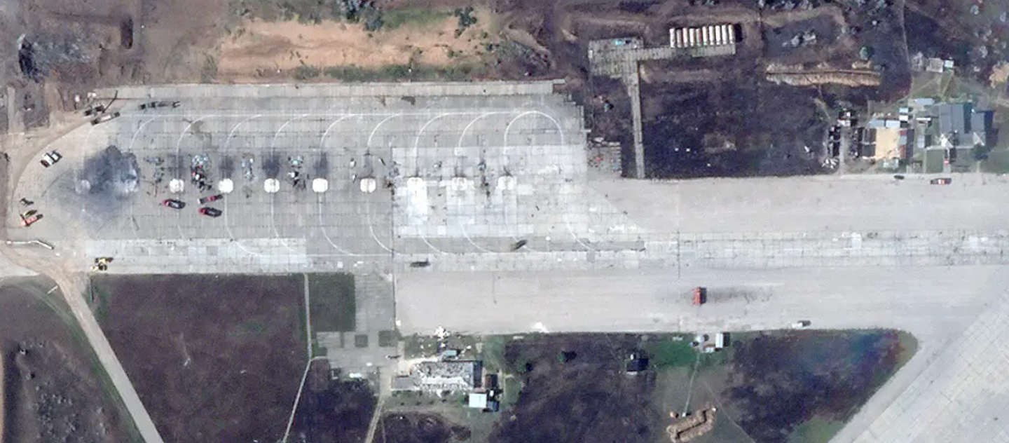 A close-up of the ramp at the southwestern end of Saky airbase on August 10, 2022, showing the remains of multiple aircraft. Fire trucks and other vehicles can be seen, as well. There is visible damage to the structures to the immediate south and east, too.&nbsp;<em>PHOTO © 2022 PLANET LABS INC. ALL RIGHTS RESERVED. REPRINTED BY PERMISSION</em>