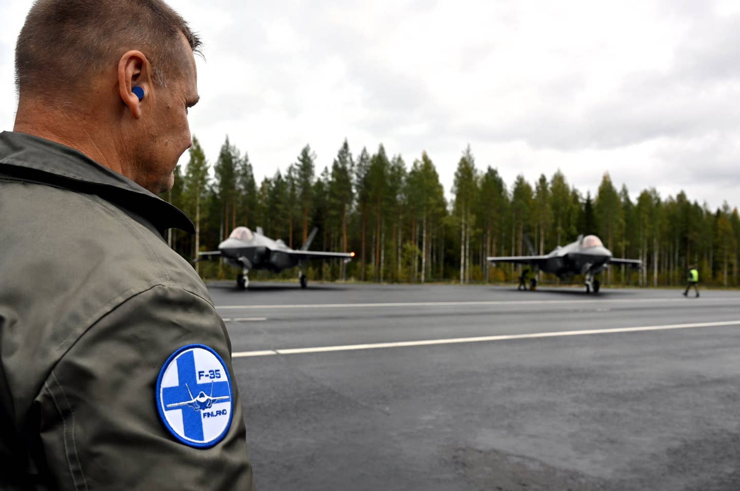 A member of Finland's armed forces wearing an F-35 patch stands in front of two Norwegian Joint Strike Fighters during Baana 23. <em>Finnish Defense Forces</em>