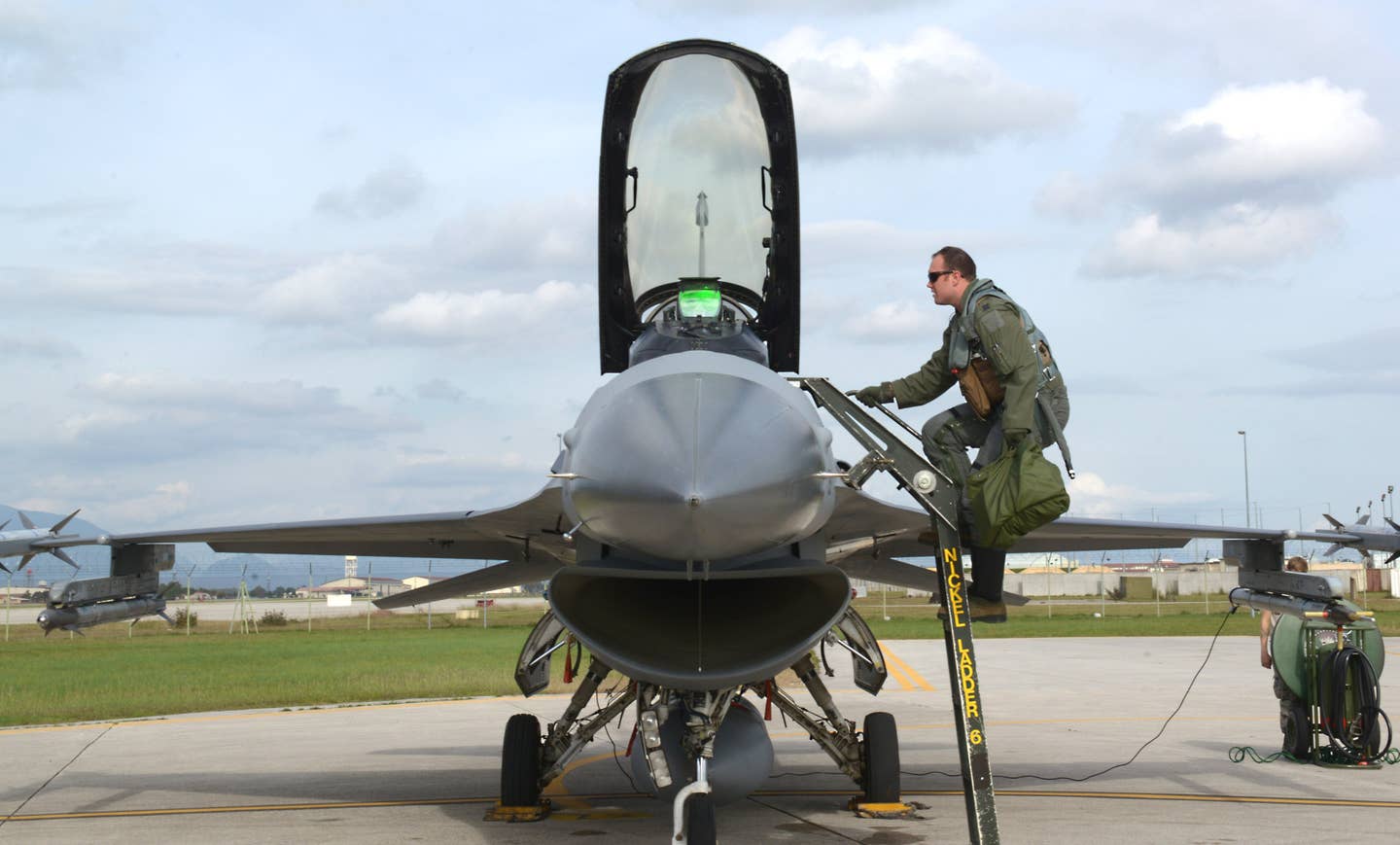 A US Air Force pilot climbs into the cockpit of an F-16 at Aviano Air Base in Italy using a typical external boarding ladder. <em>USAF</em>