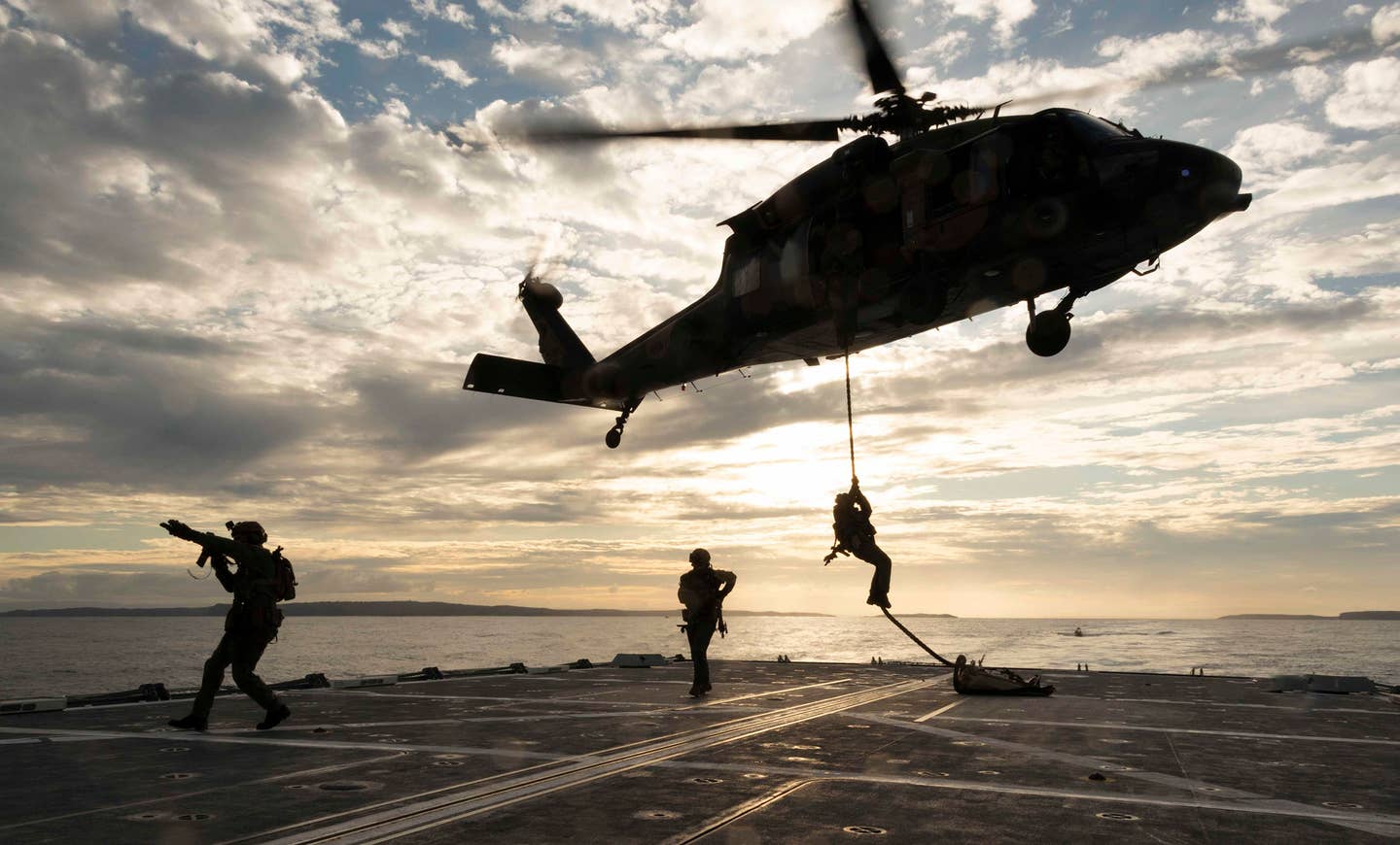 Australian Army soldiers from the 2nd Commando Regiment conduct a fast-rope descent from a 6th Aviation Regiment S-70A-9 Black Hawk helicopter onto a Royal Australian Navy vessel during maritime counterterrorism training in Jervis Bay, southern New South Wales, in early June 2020. <em>COMMONWEALTH OF AUSTRALIA, DEPARTMENT OF DEFENSE</em>