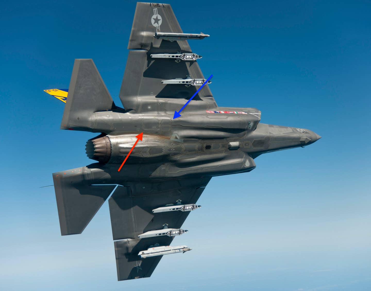 An annotated photo of an F-35C, showing the dual flip-open infrared countermeasures dispenser door (blue arrow) and the towed decoy deployment door located just aft of it (red arrow).&nbsp;<em>Lockheed Martin</em><br>