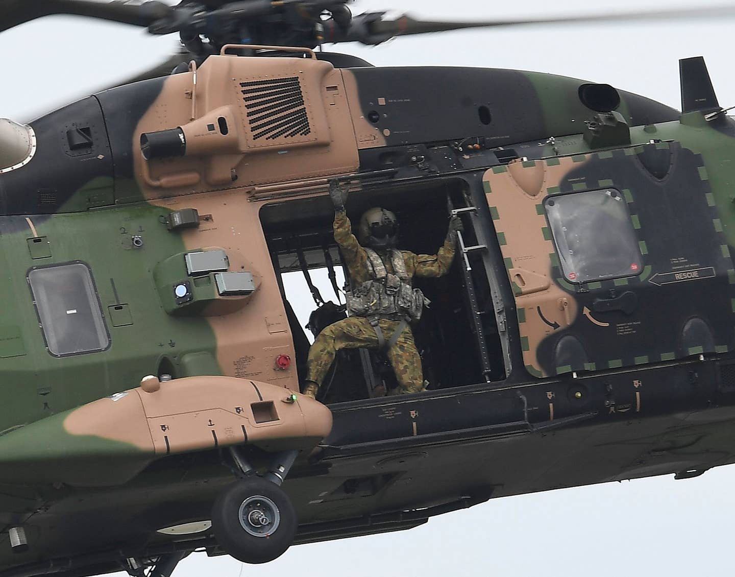 A loadmaster in an Australian Army MRH90 Taipan helicopter waves to the crowd as it performs during the T150 Defense Force Air Show on October 15, 2016, in Townsville, Australia. <em>Photo by Ian Hitchcock/Getty Images</em>