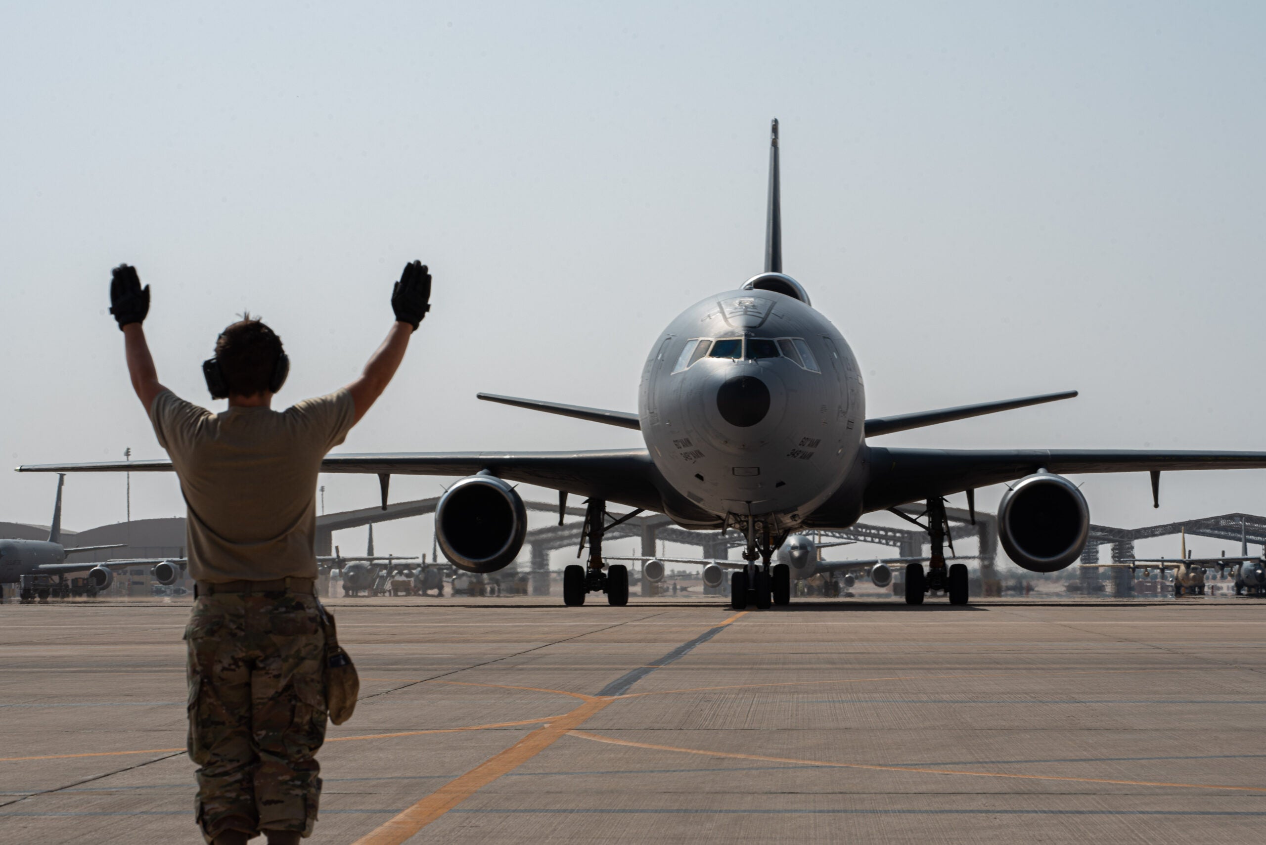 A U.S. Airman from the 378th Expeditionary Aircraft Maintenance Squadron directs a taxiing KC-10 Extender assigned to the 908th Air Refueling Squadron after the aircraft returned from the airframe's final combat sortie on Prince Sultan Air Base, Oct. 3, 2023. The flight served as a capstone for the KC-10 after over 30 years of service within the U.S. Air Forces Central (AFCENT) Area of Responsibility. By September 2024, the U.S. Air Force's fleet of KC-10s will be decommissioned and gradually replaced by the KC-46 aircraft. (U.S. Air Force photo by Tech. Sgt. Alexander Frank)