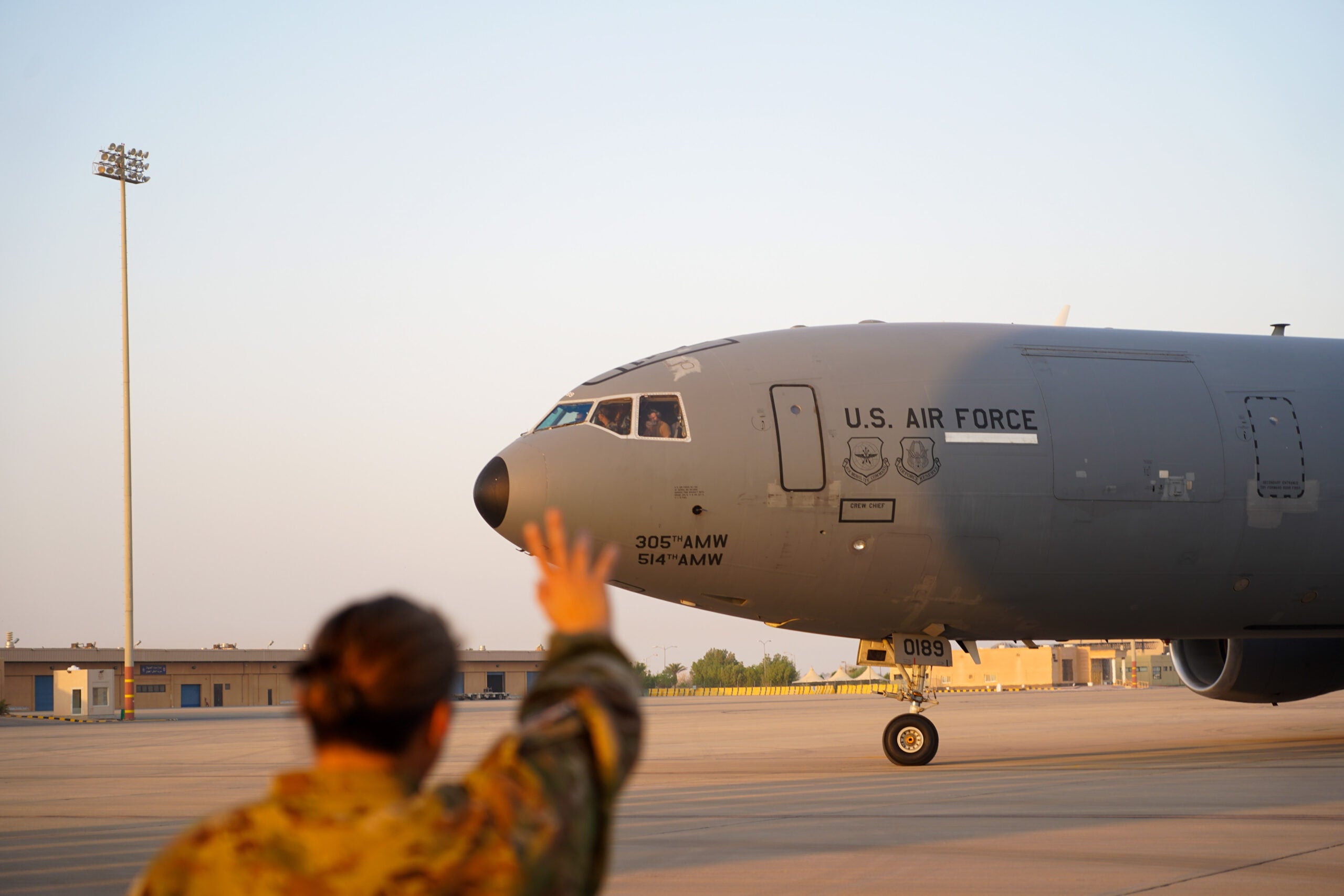 A U.S. Airman waves to a KC-10 as it departs after conducting the airframe's final combat deployment at Prince Sultan Air Base (PSAB), Kingdom of Saudi Arabia, Oct. 5, 2023. The departure of the KC-10 at PSAB marked the end of the airframe's over 30 years of service within the U.S. Air Forces Central (AFCENT) Area of Responsibility. By September 2024, the U.S. Air Force's fleet of KC-10s will be decommissioned and gradually replaced by the KC-46 aircraft. (U.S. Air Force photo by Tech. Sgt. Alexander Frank)