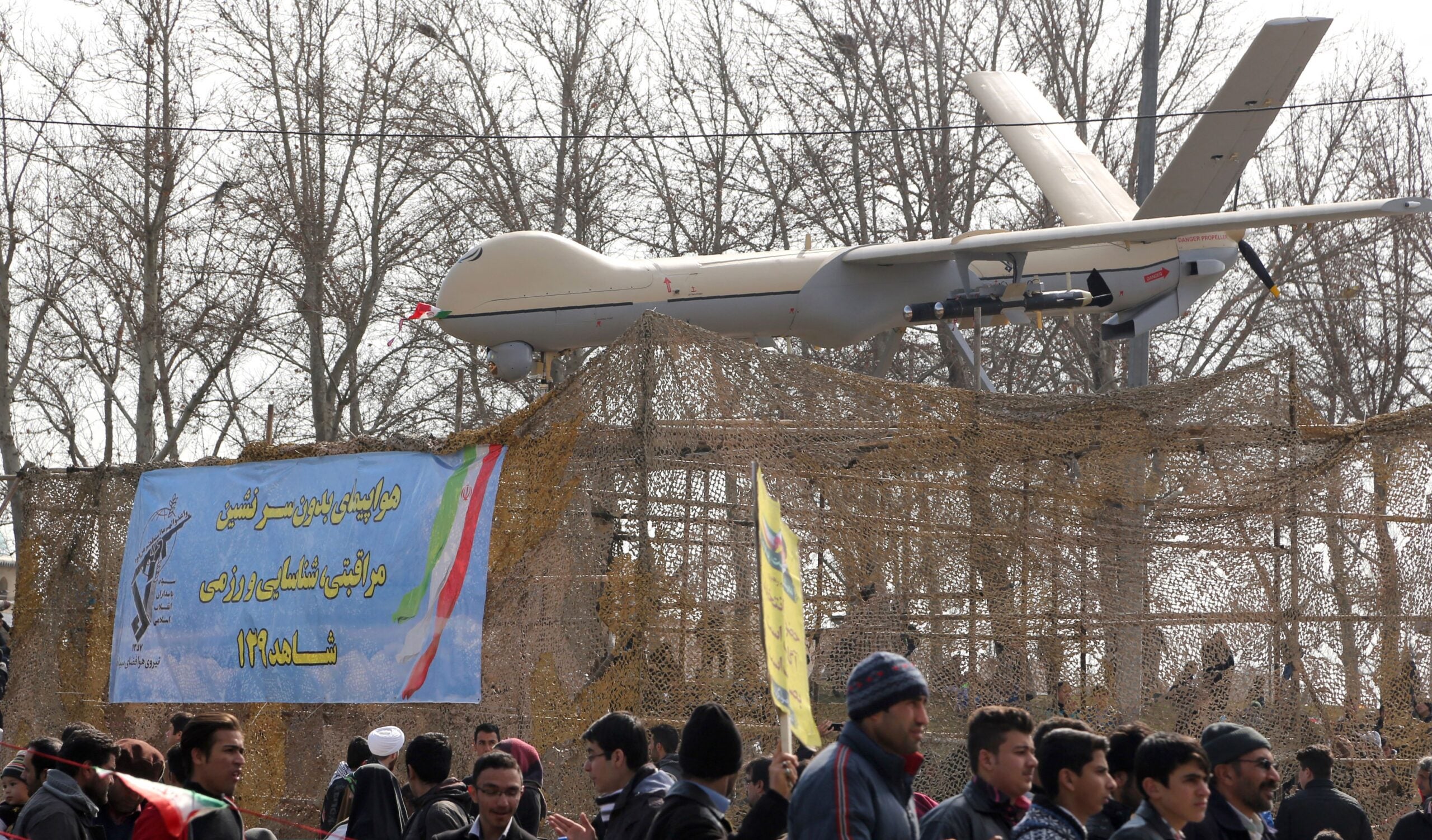 Iranians walk past Iran's Shahed 129 drone during celebrations in Tehran to mark the 37th anniversary of the Islamic revolution on February 11, 2016. Iranians waved "Death to America" banners and took selfies with a ballistic missile as they marked 37 years since the Islamic revolution, weeks after Iran finalised a nuclear deal with world powers. (Photo by ATTA KENARE / AFP) (Photo by ATTA KENARE/AFP via Getty Images)