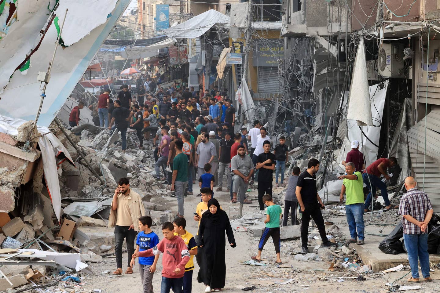 Palestinians walk amid the rubble of destroyed and damaged buildings in the heavily bombarded city center of Khan Yunis in the southern Gaza Strip following overnight Israeli shelling, on October 10, 2023.  (Photo by SAID KHATIB / AFP) (Photo by SAID KHATIB/AFP via Getty Images)