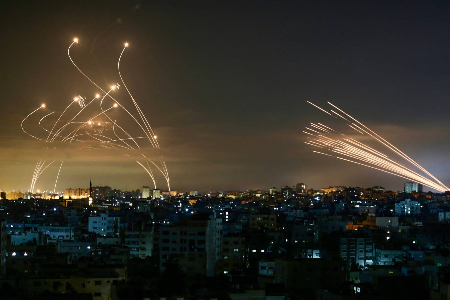 The Israeli Iron Dome missile defense system (L) intercepts rockets (R) fired by the Hamas movement towards southern Israel from Beit Lahia in the northern Gaza Strip as seen in the sky above the Gaza Strip overnight on May 14, 2021. <em>Photo by ANAS BABA/AFP via Getty Images</em>