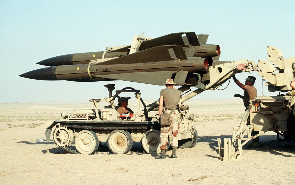 Members of the US Army load Hawk missiles onto a launcher using a specialized reloading vehicle during the First Gulf War. <em>US Army</em>
