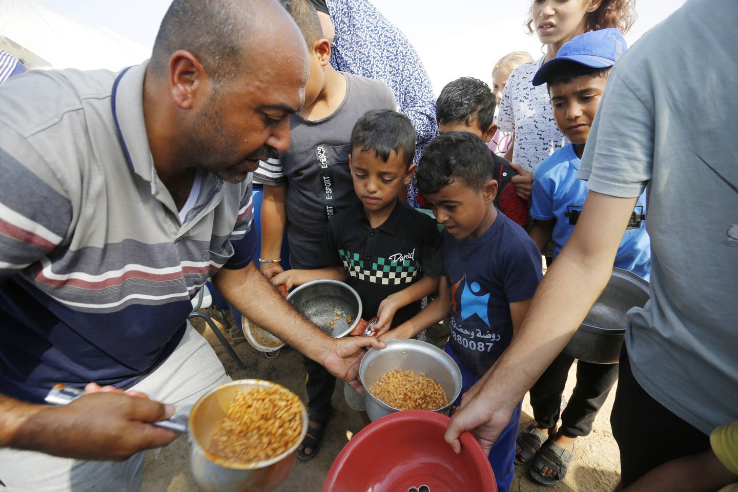 Palestinians including children are served food by United Nations Agency for Palestine Refugees (UNRWA) officials as they took refuge in UNRWA camp to flee Israeli attacks in Khan Yunis, Gaza on October 24, 2023. (Photo by Ashraf Amra/Anadolu via Getty Images)