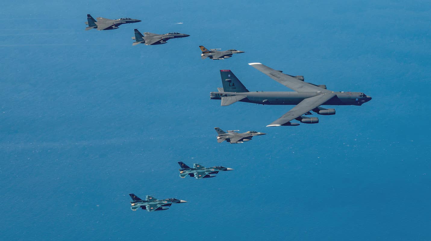 60-0021, with its white wing tips prominently visible, flying together with, top to bottom, South Korean Air Force F-15Ks, US Air Force F-16s, and Japan Air Self Defense Force F-2s on October 22. <em>USAF</em>