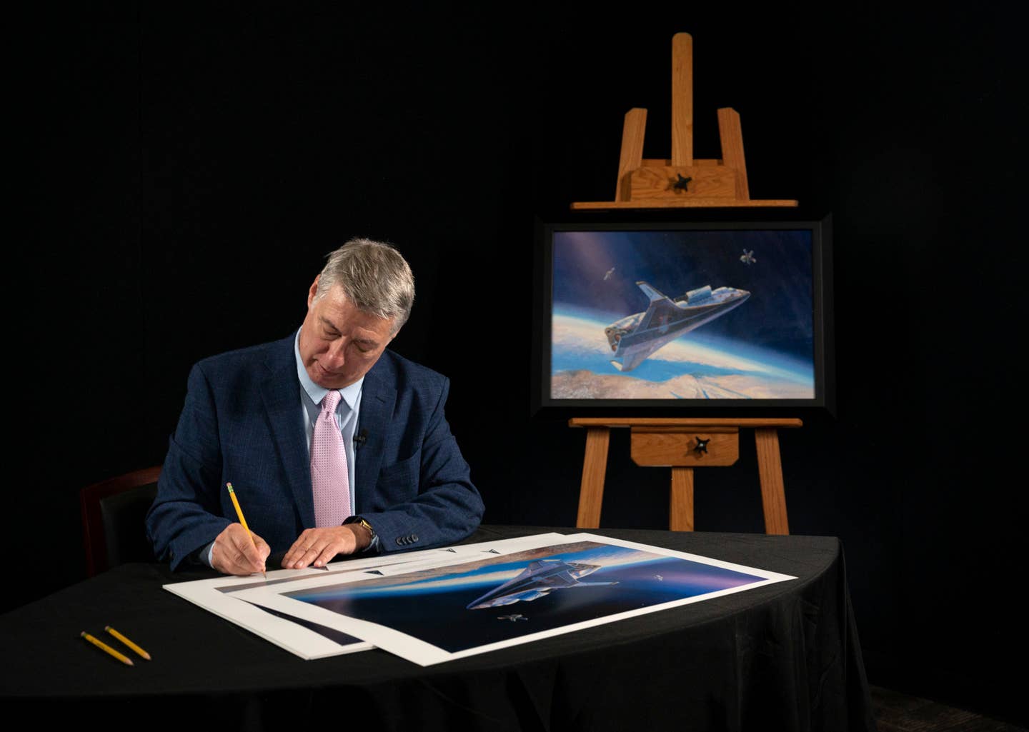 Aerospace artist Rick Herter signs prints of his painting for the U.S. Space Force's Space Operations Command at the unveiling ceremony. <em>US Space Force</em>