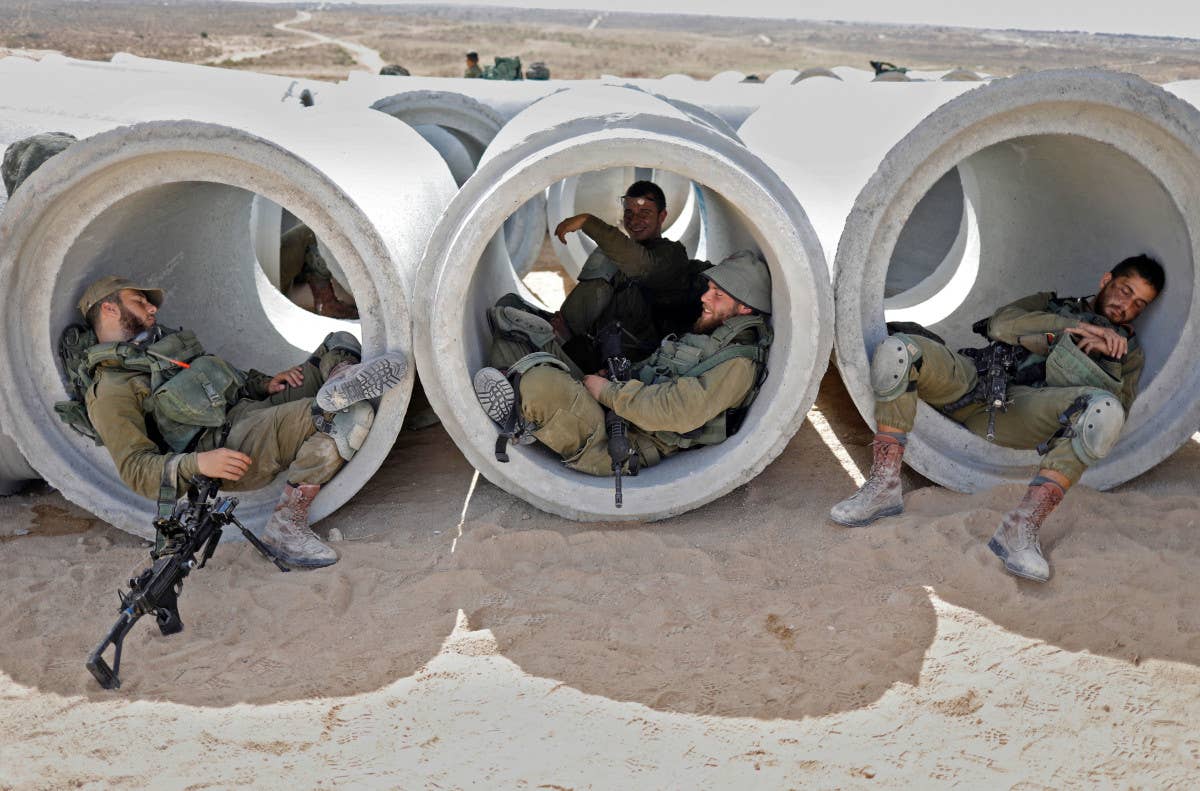 Israeli forces rest in concrete pipes while training at Tze’Elim army base's "Little Gaza" in 2018. <em>MENAHEM KAHANA/AFP via Getty Images</em>
