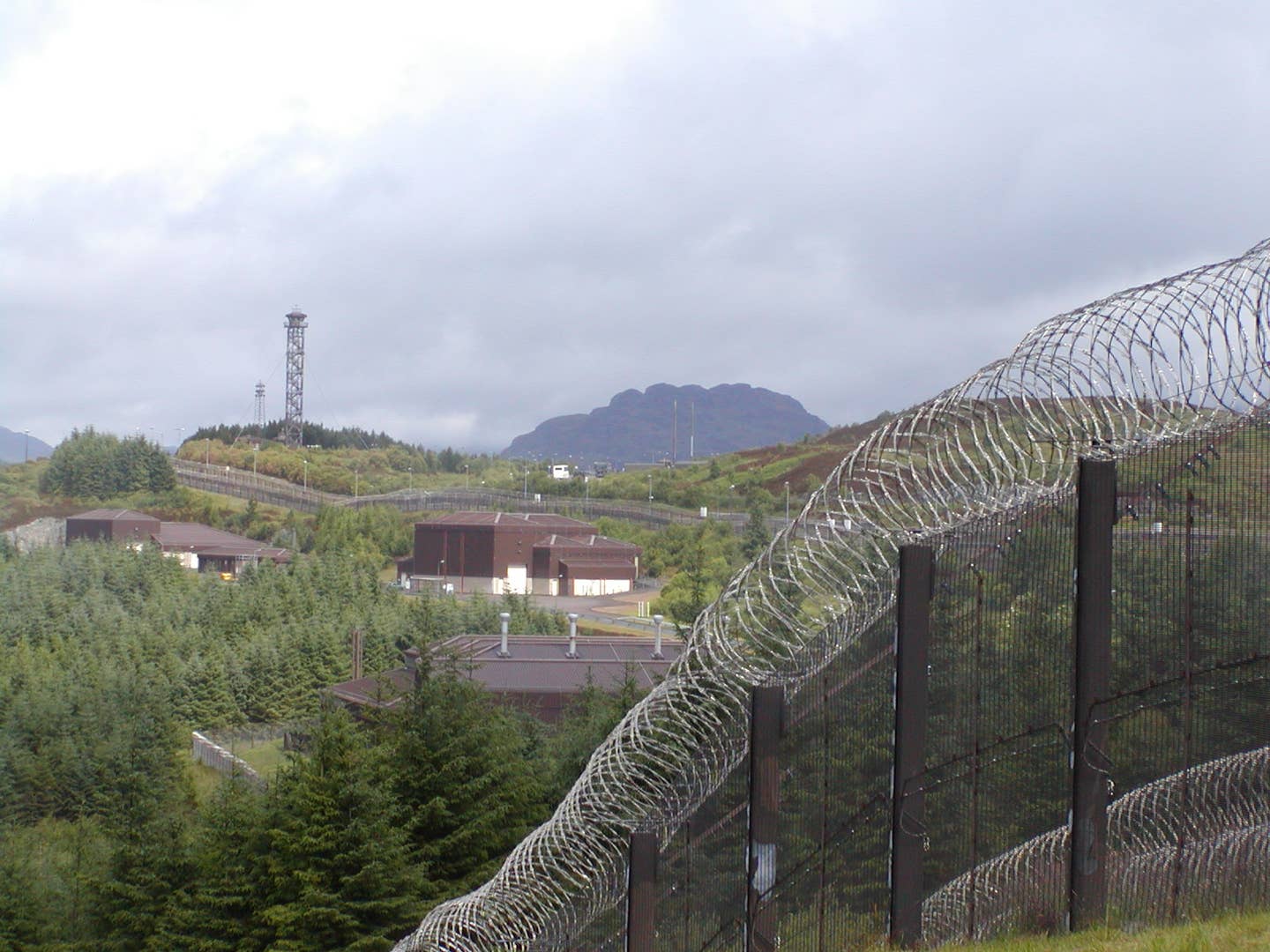 Perimeter fence and buildings at RNAD Coulport, Loch Long, Scotland, 2013. <em>Unknown author via</em> <em>Wikimedia Commons</em>