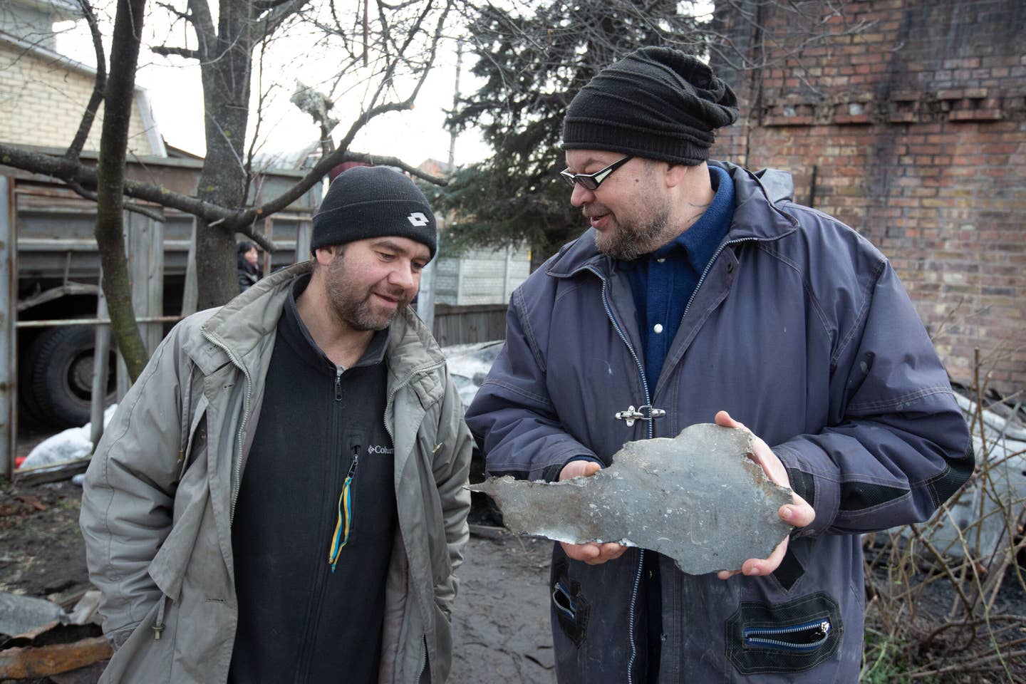Men look at a piece of a cruise missile that destroyed their neighbor’s house in a village outside Kyiv, Ukraine. Russia launched a massive missile attack on Ukraine on December 29, 2022. <em>Photo by Oleksii Chumachenko/Anadolu Agency via Getty Images</em>