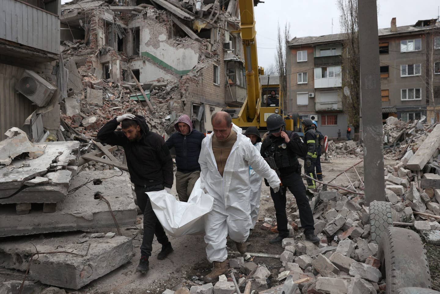 Rescue workers carry the remains of a person killed in front of a heavily damaged residential building following a Russian strike, in the town of Selydove, Donetsk region, on November 15, 2023, amid the Russian invasion of Ukraine. <em>Photo by ANATOLII STEPANOV/AFP via Getty Images</em>