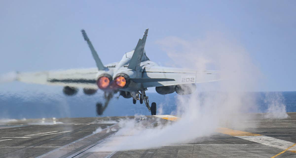 Steam is seen rising from one of the catapult tracks on the U.S. Navy's <em>Nimitz</em> class aircraft carrier USS <em>Abraham Lincoln</em> as an EA-18G Growler electronic warfare jet is launched. <em>USN</em>