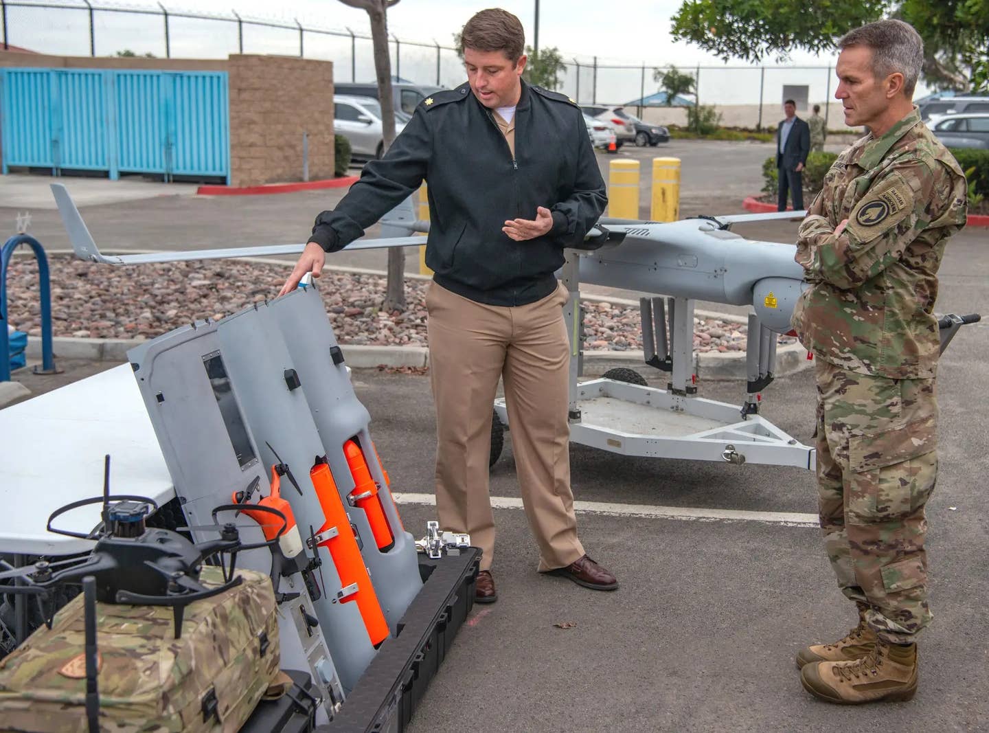 An individual assigned to Naval Special Warfare Command, at left, shows payload modules for the RQ-21 Blackjack, including one holding a small quadcopter-type drone, to U.S. Army Gen. Richard Clarke, commander of U.S. Special Operations Command, December 13, 2021.&nbsp;<em>U.S. Navy</em>