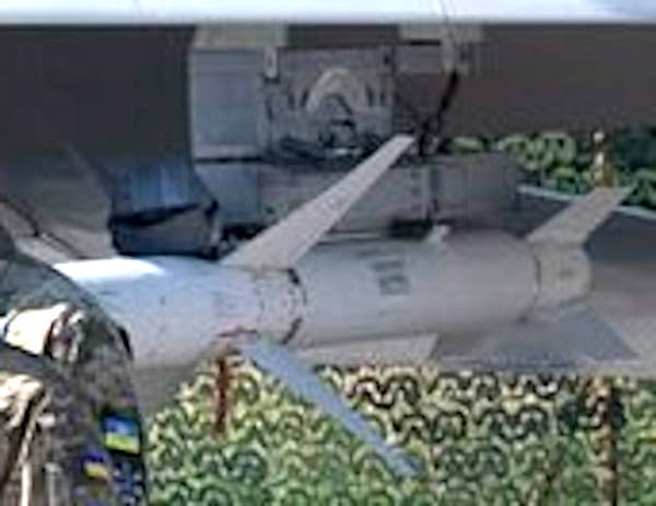 A low-quality close-up showing an AGM-88 under the wing of a Ukrainian Su-27. A helmet is seen resting on top of the missile in front the pylon. <em>Government of Ukraine via X</em>
