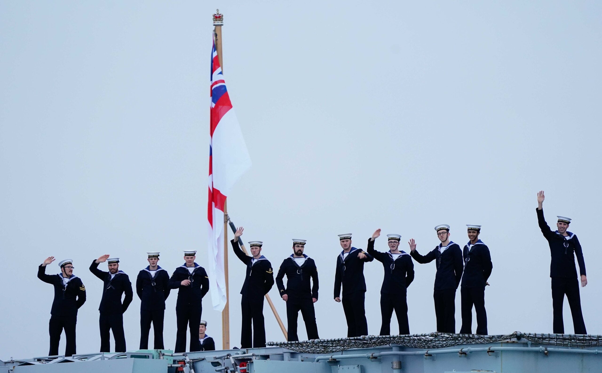 Sailors on board wave towards the Round Tower as the Royal Navy's aircraft carrier HMS Queen Elizabeth returns to Portsmouth Naval Base following her deployment to the Far East. Picture date: Thursday December 9, 2021. (Photo by Andrew Matthews/PA Images via Getty Images)