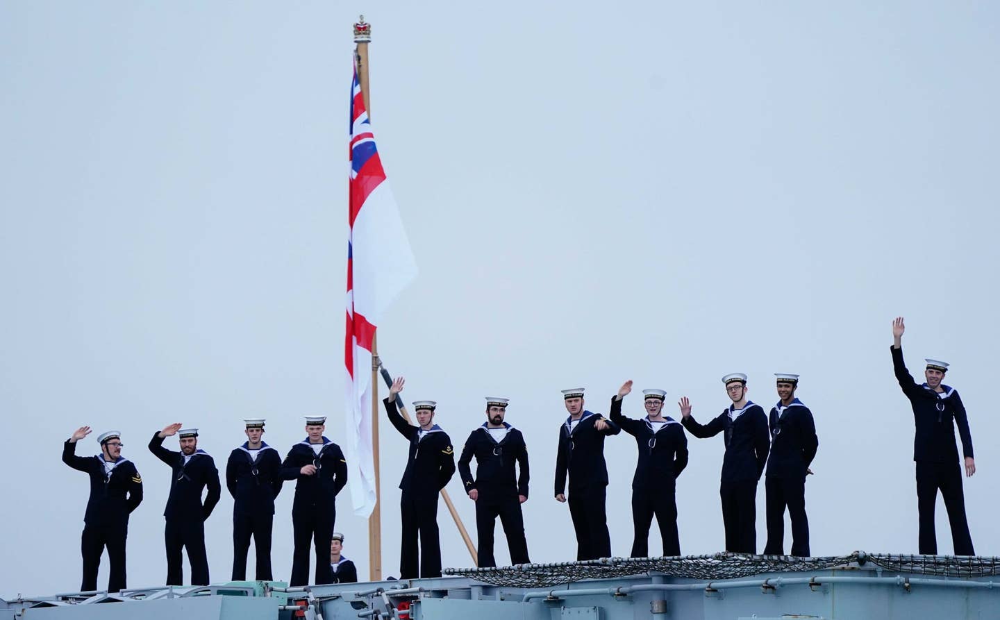 Sailors on board wave towards the Round Tower as the Royal Navy's aircraft carrier HMS Queen Elizabeth returns to Portsmouth Naval Base following her deployment to the Far East, December 9, 2021. <em>Photo by Andrew Matthews/PA Images via Getty Images</em>