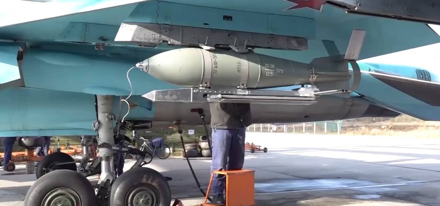 A screen capture from an earlier video released by the Russian Ministry of Defense showing a UMPK-equipped FAB-500 M62 being loaded onto an Su-34 Fullback combat jet. Note the difference in the tail fin configuration between this bomb and the one in footage released today. <em>Russian MoD capture</em>