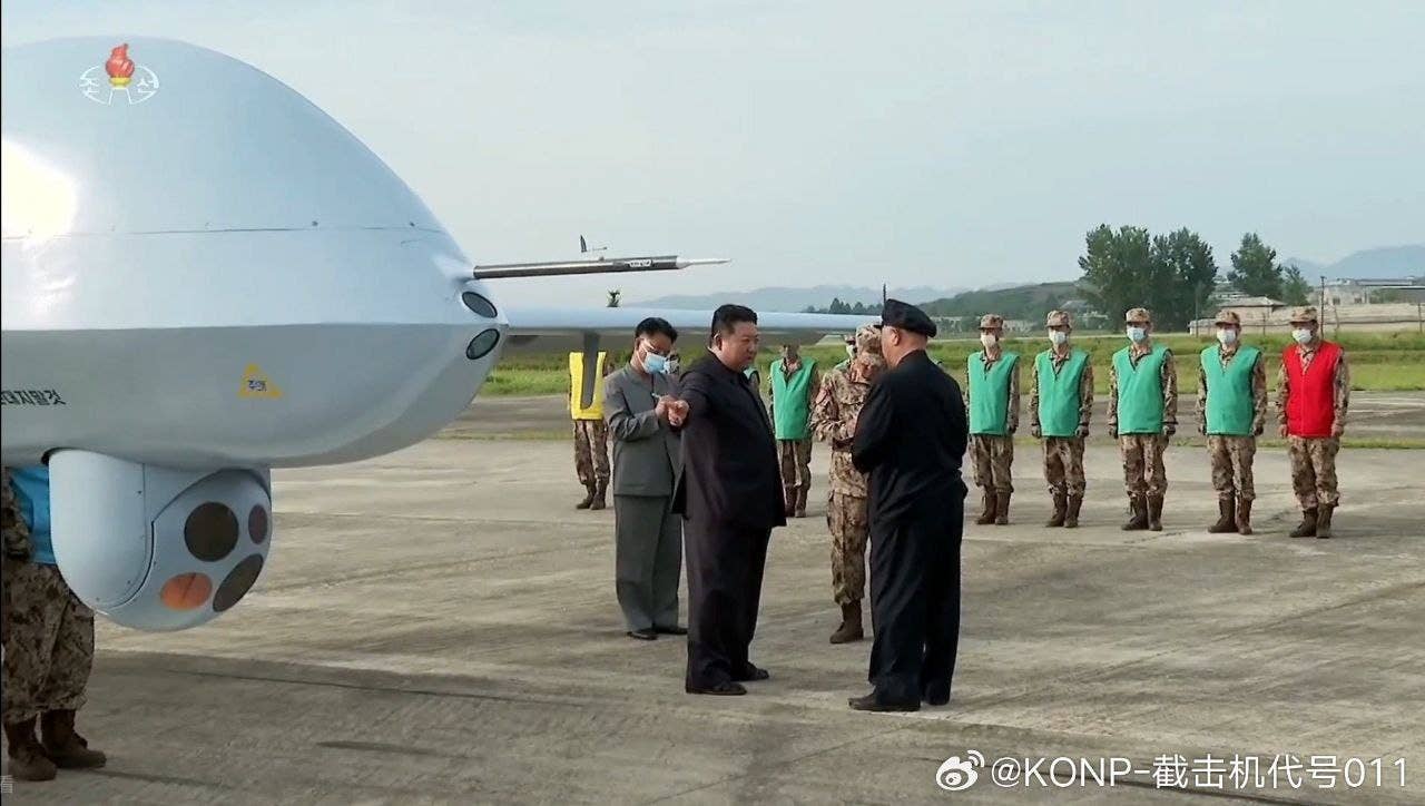 Kim Jong Un stands near the front of the Saetbyol-9 drone and its gimbled sensor pod. (Via Weibo)