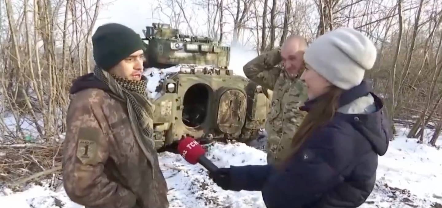 Serhiy (left) and Oleksandr are interviewed outside their Bradley Fighting Vehicle (TCH screencap)
