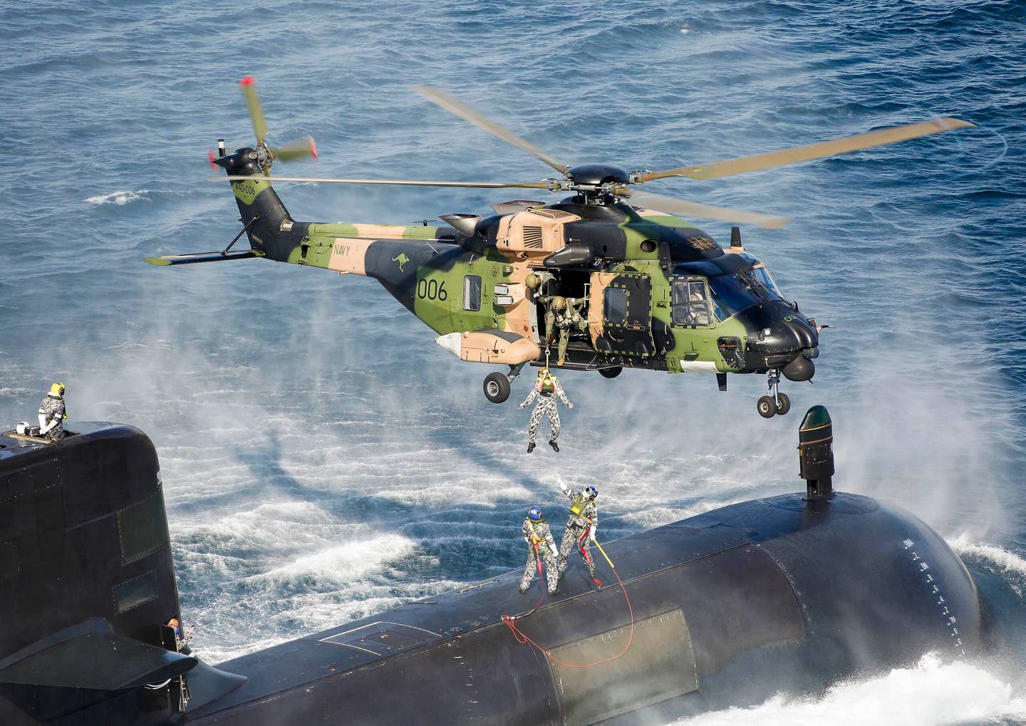 A Royal Australian Navy 808 Squadron NH-90 Tactical Transport Helicopter conducts a personnel winch from an Australian <em>Collins </em>class diesel-electric submarine prior to the early retirement of the Navy’s NH-90s in April 2022. <em>Commonwealth of Australia, Department of Defense</em>